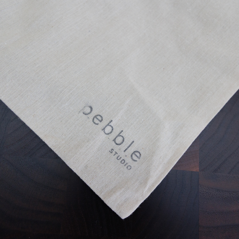 Pebble Studio logo on a calico bag.
