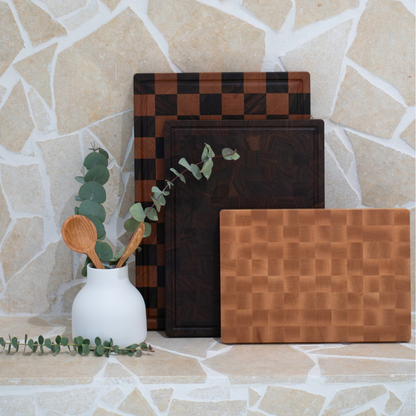 Set of wooden chopping boards with a vase of greenery on a stone surface