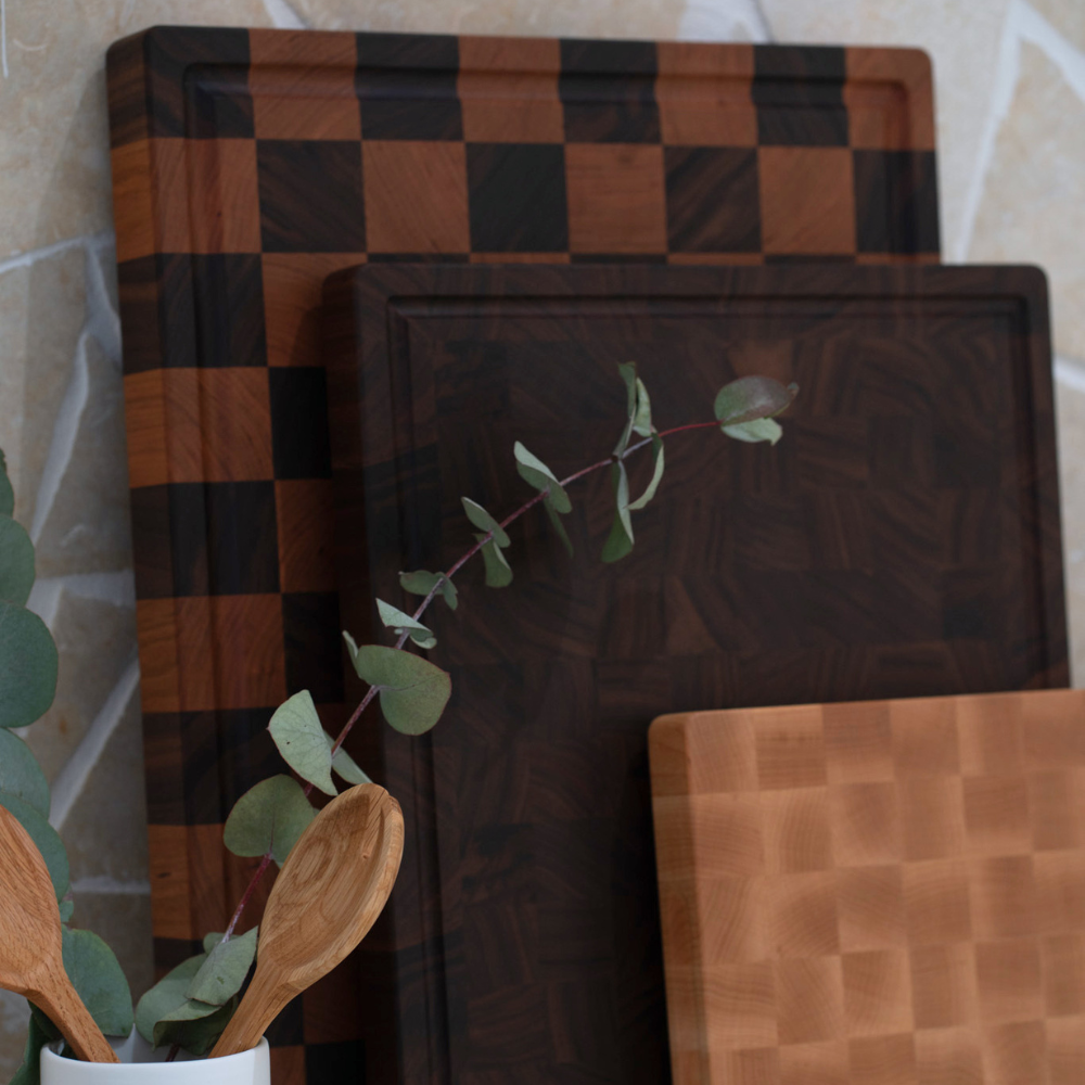 Set of wooden chopping boards with a checkered pattern on a stone surface.