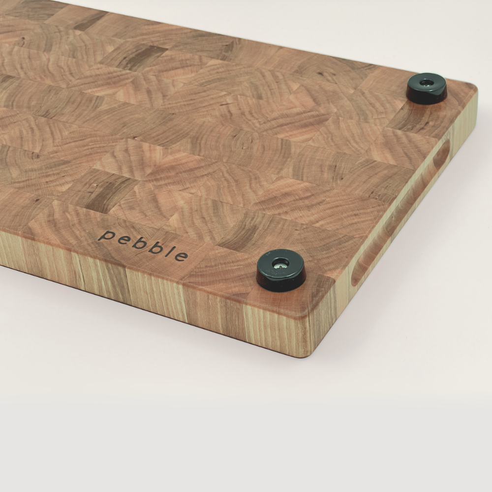 Wooden cutting board with 'pebble' branding on a white background