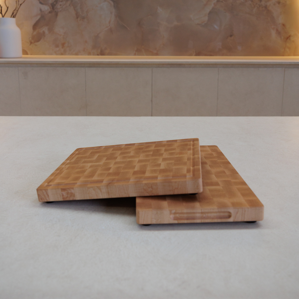 Two wooden cutting boards stacked on a light-coloured surface with a marble wall in the background.