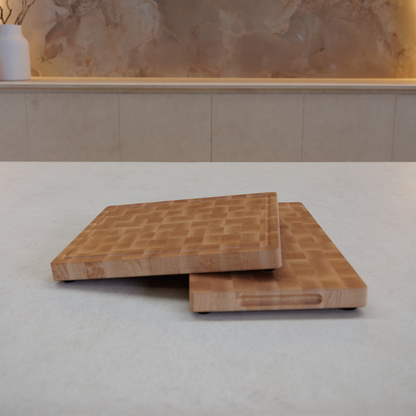 Two wooden cutting boards stacked on a light-coloured surface with a marble wall in the background.