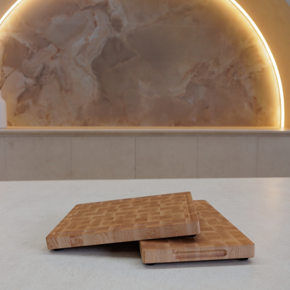 Two wooden cutting boards on a light surface with a marble backsplash.