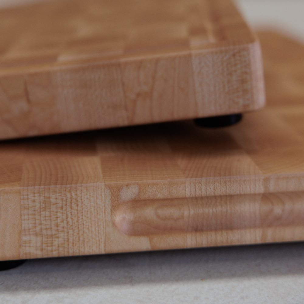 Close-up of two wooden cutting boards stacked on a neutral background