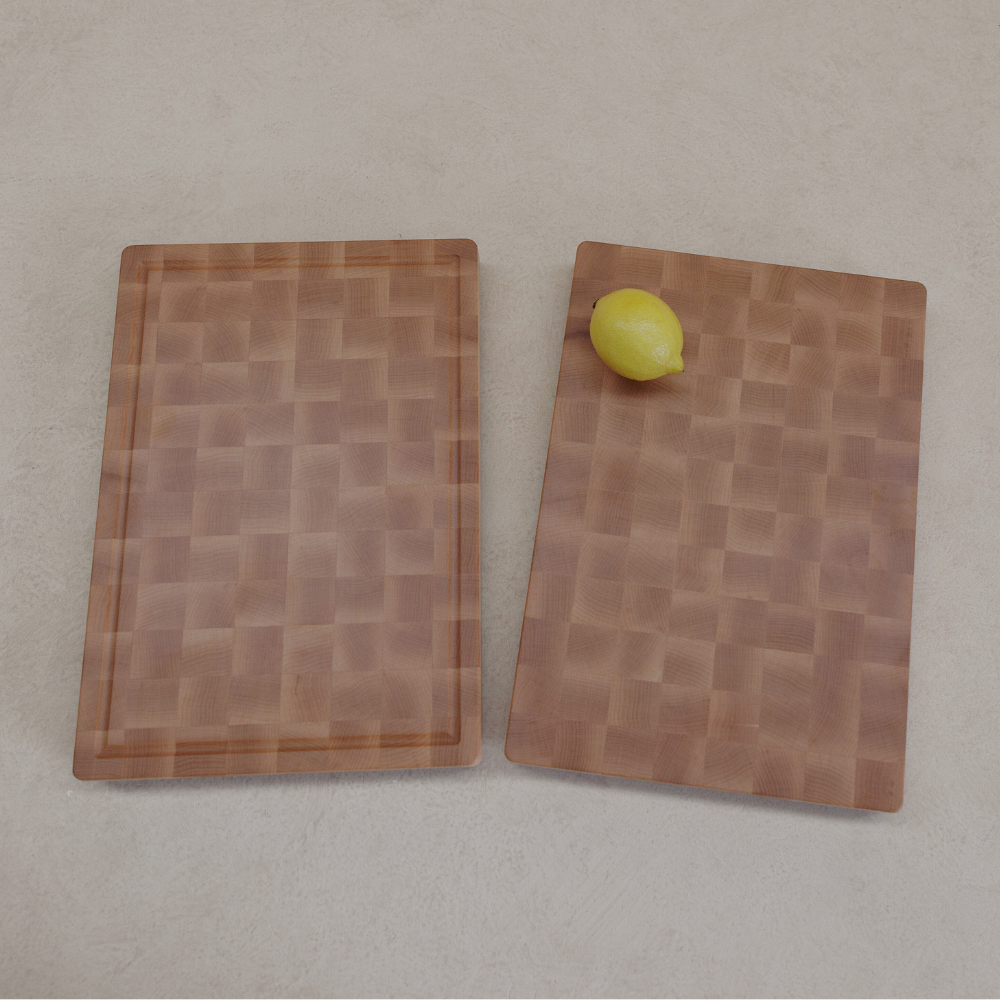 Two wooden cutting boards with a lemon on a grey background