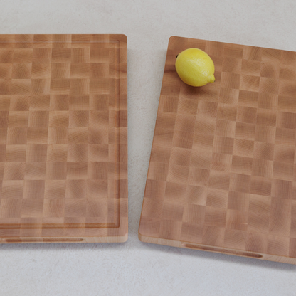 Two wooden cutting boards with a lemon on a light grey surface
