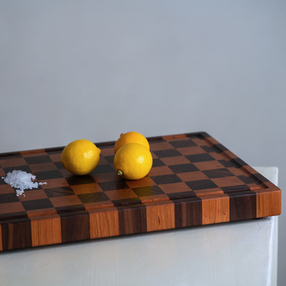 Wooden checkered chopping board with lemons on a neutral background