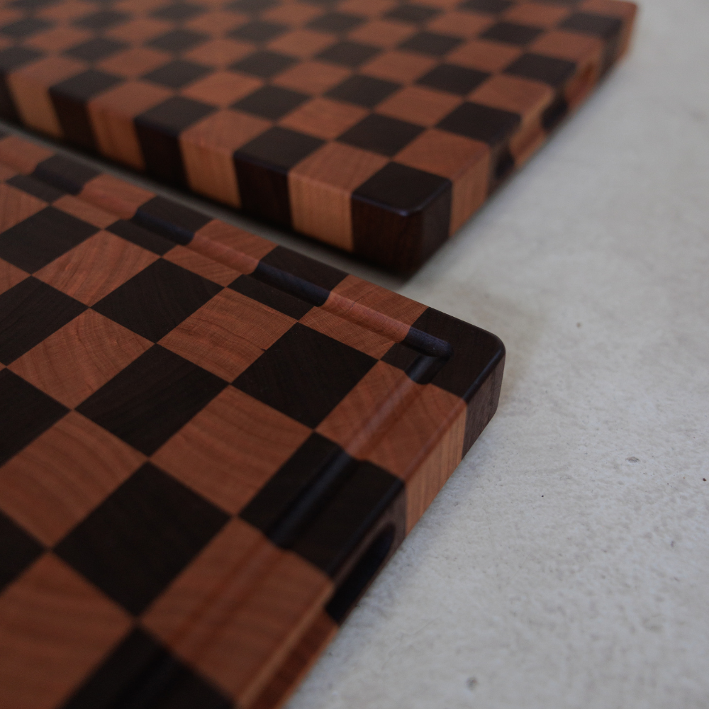 Two wooden chopping boards with a checkered pattern on a light grey surface.