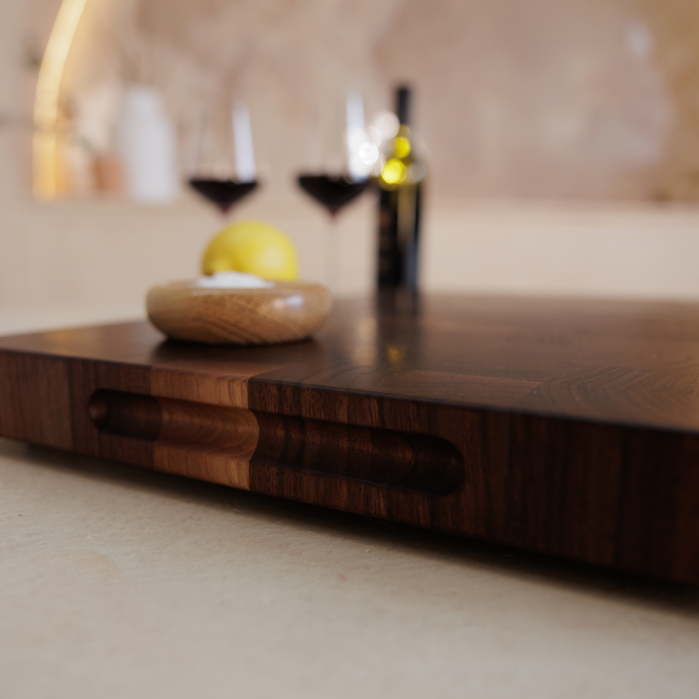 Wooden chopping board with a lemon and small dish on a blurred background.