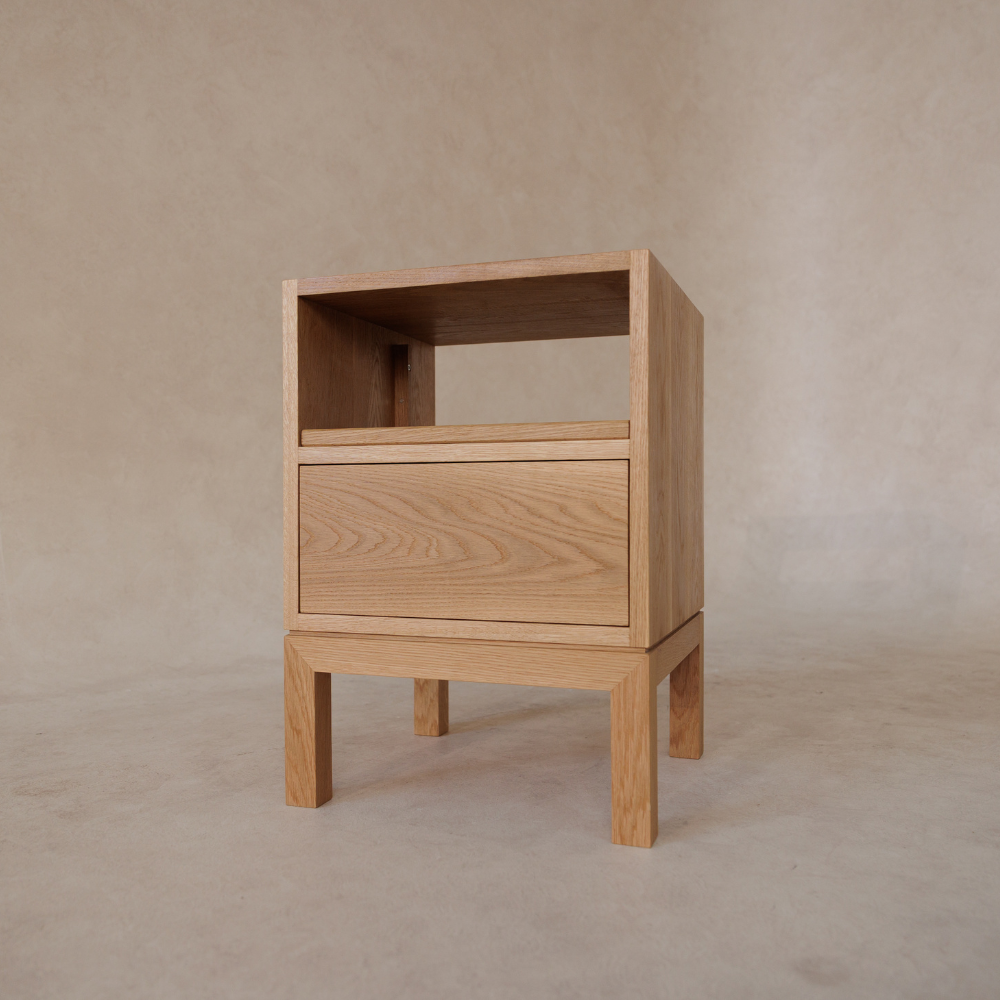 Wooden side table with a drawer against a beige background