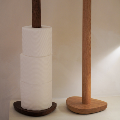 Two wood toilet roll holders with three rolls of toilet paper on a neutral background