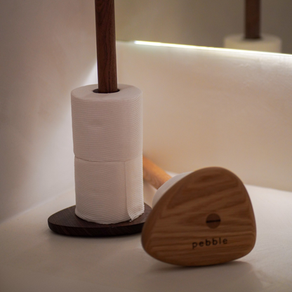 Wood toilet roll holder with toilet paper on a white surface.