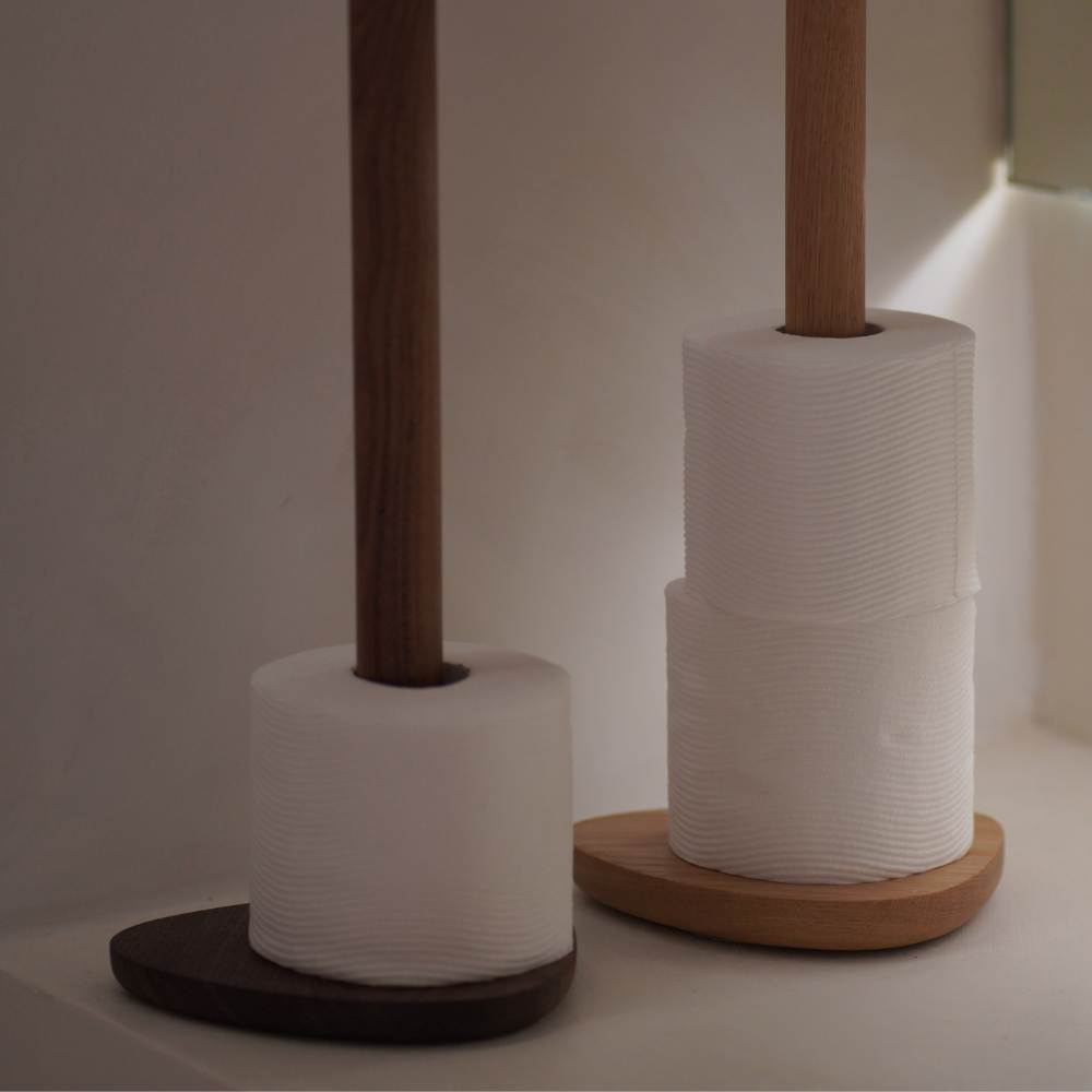 Two toilet roll holders with white toilet paper on a neutral background
