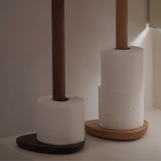 Two toilet roll holders with white toilet paper on a neutral background