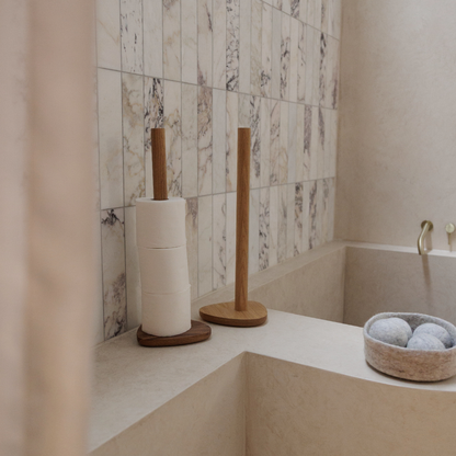 Bathroom corner with toilet paper holder, with decorative wool bowl  holding dryer balls.