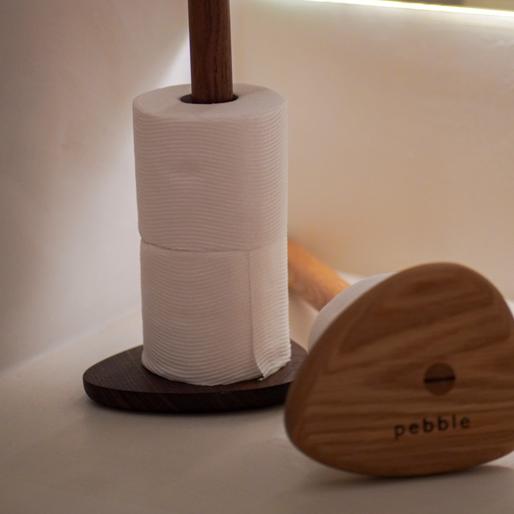 Two wood toilet roll holders with toilet paper on a neutral background