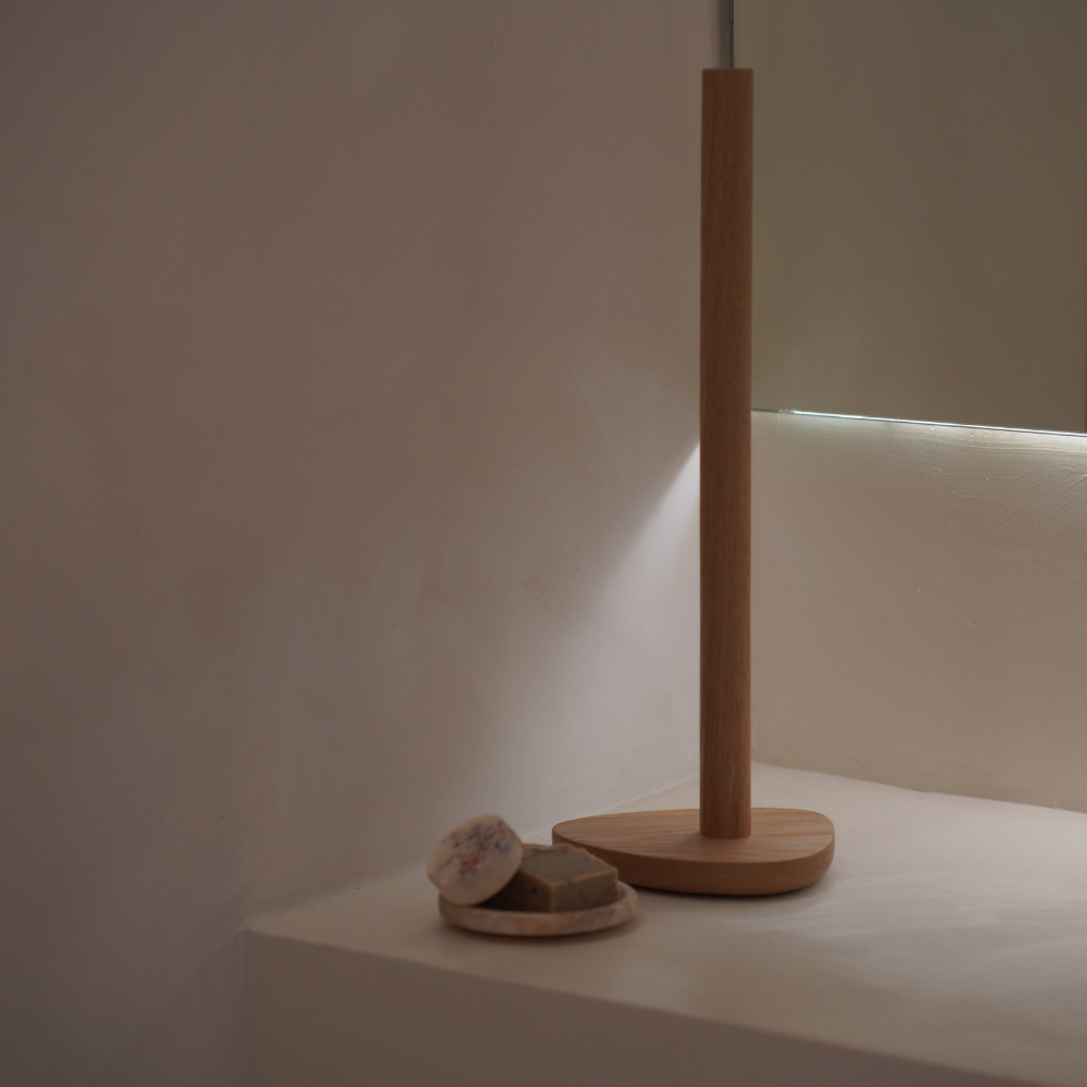 Wood toilet roll holder and soap on a white surface with a neutral background