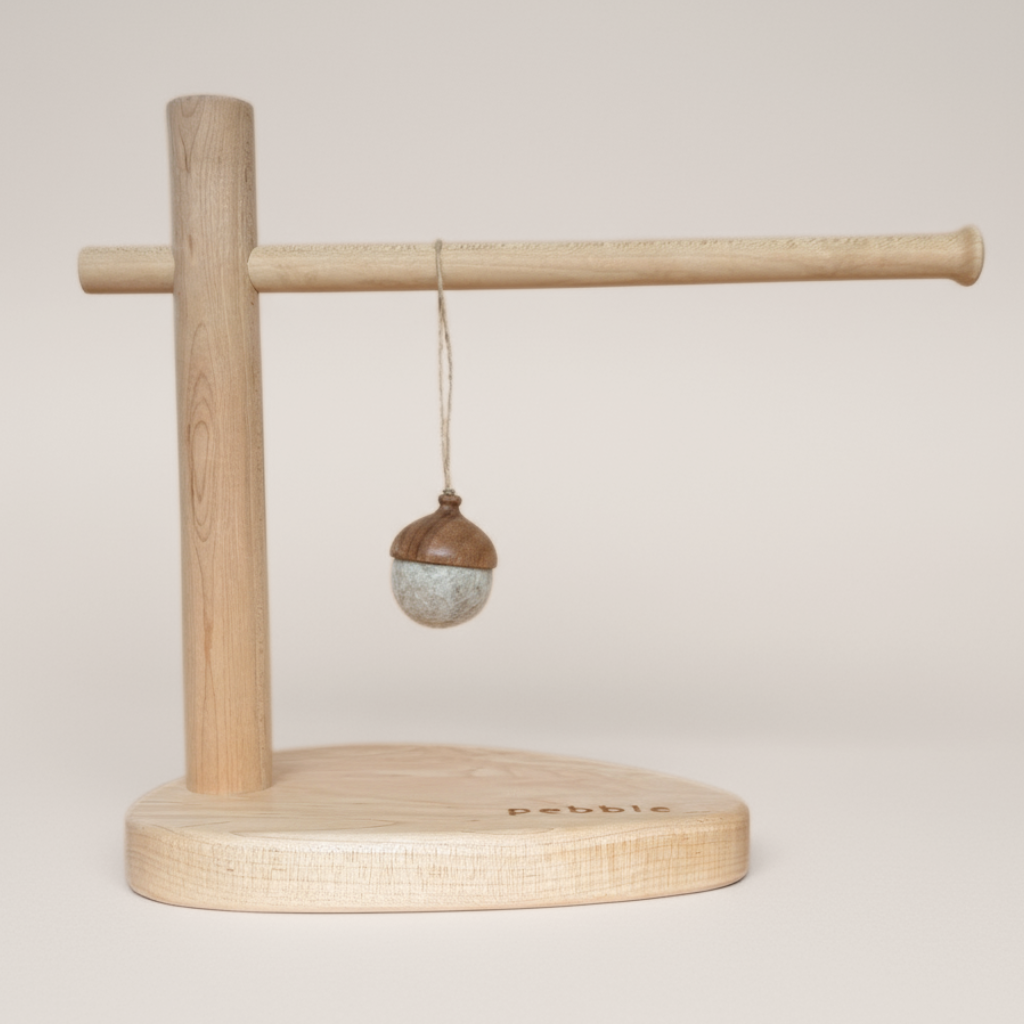 Hand turned walnut and marbled beige felt acorn ornament with jute loop, hanging from a wooden stand. Australian handmade natural Christmas decoration