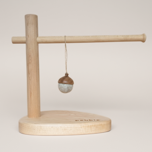 Hand turned walnut and marbled beige felt acorn ornament with jute loop, hanging from a wooden stand. Australian handmade natural Christmas decoration