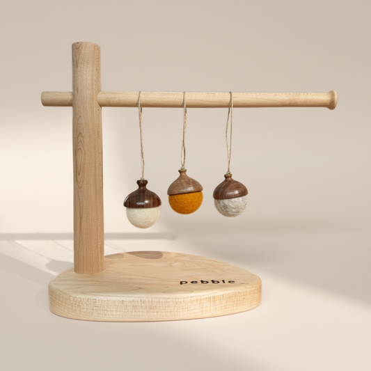 Three hand turned walnut and felt acorn ornaments with jute loop hanging from a wooden stand. Australian Made natural Christmas decoration for slow living