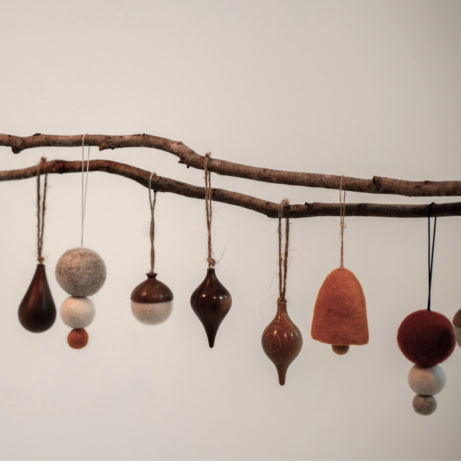 Decorative ornaments hanging from a branch against a plain background