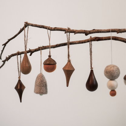 Decorative hanging ornaments on a branch against a plain background