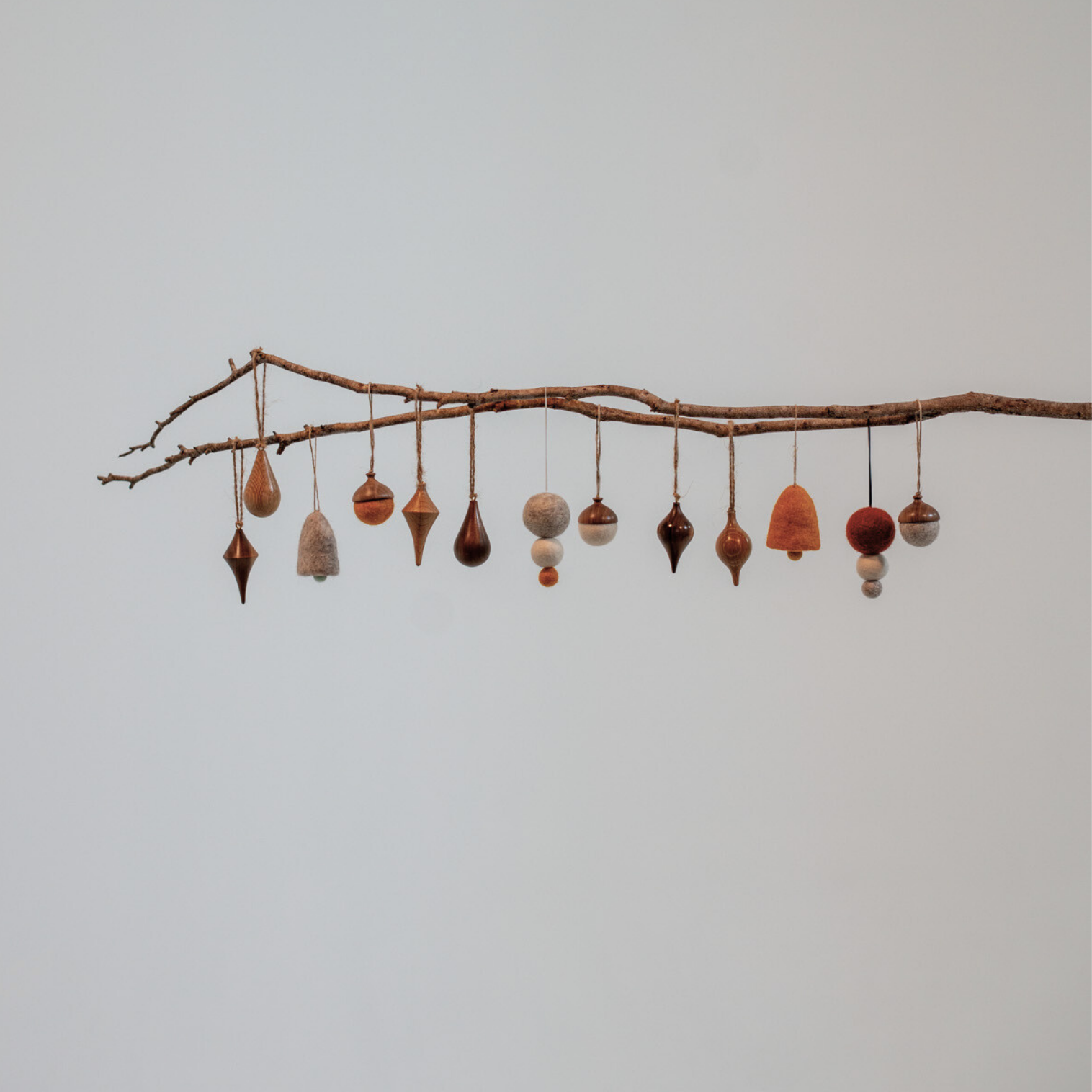 Pebble Studios Christmas decorations hanging from a branch against a plain background