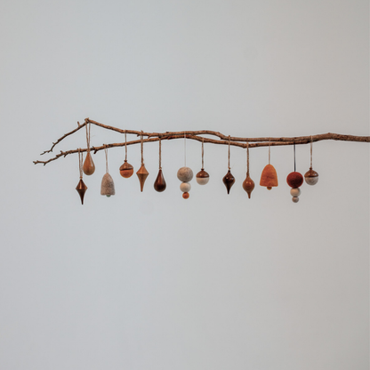 Pebble Studios Christmas decorations hanging from a branch against a plain background