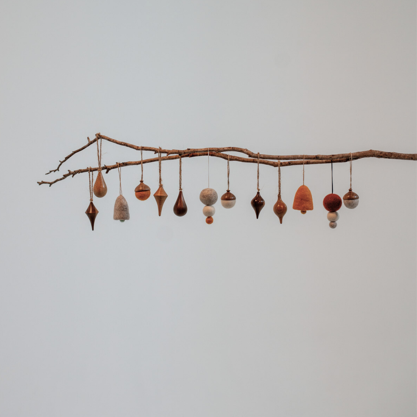 Pebble Studios Christmas decorations hanging from a branch against a plain background