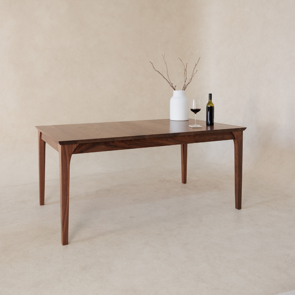 Wooden dining table with a vase and wine bottle on a beige background