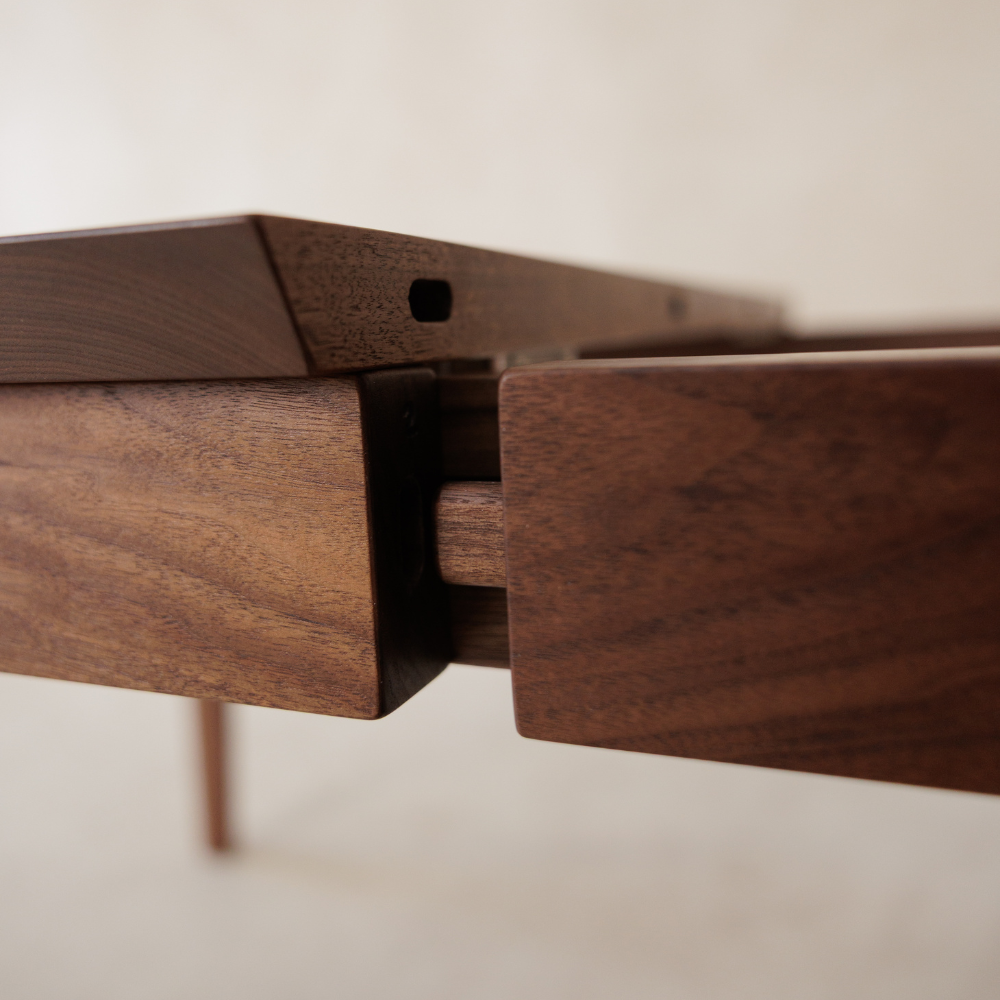 Close-up of a wooden table extension joinery detail on a plain background