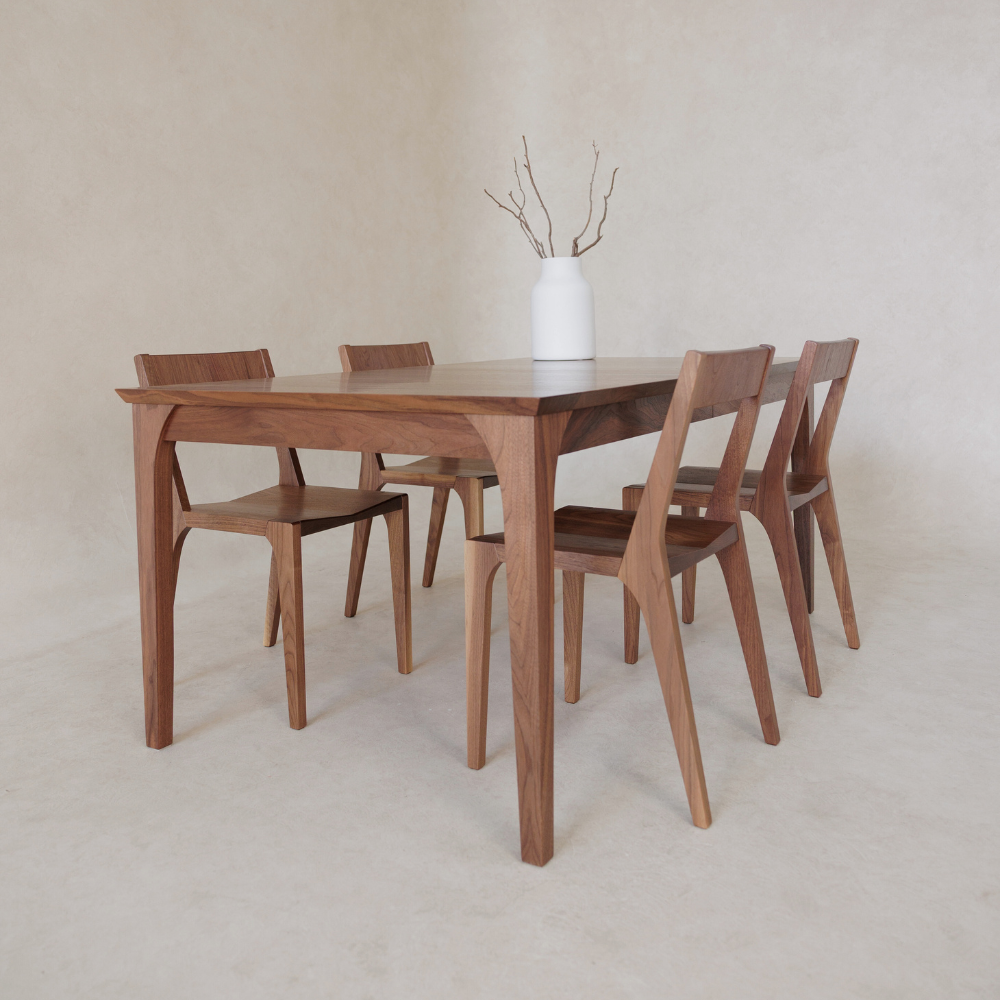 Wooden dining table with four chairs on a plain background