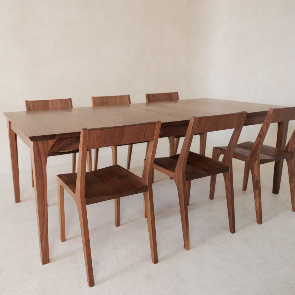 Wooden dining table with six matching chairs on a plain background