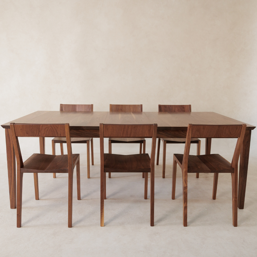 Wooden dining table with six matching chairs on a plain background