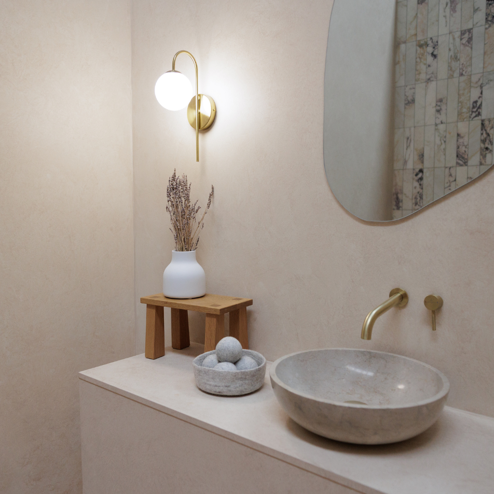 Bathroom interior with a stone sink, wooden stool, and decorative items.