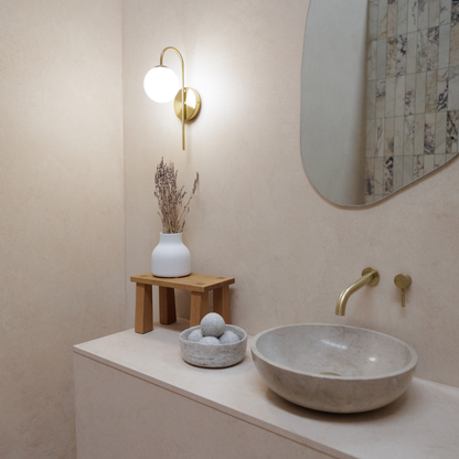 Bathroom interior with a stone sink, wooden stool, and decorative items.