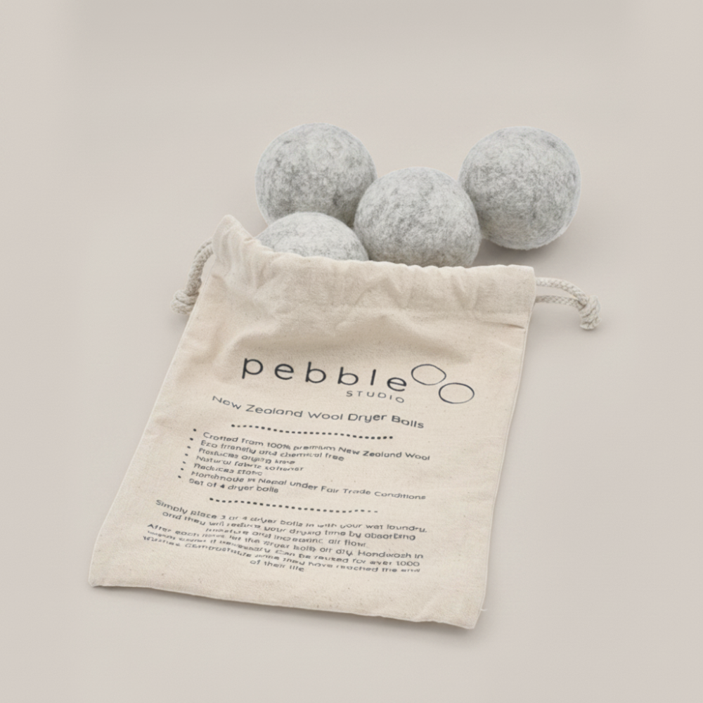Four grey wool dryer balls with a drawstring bag labelled 'pebble studio' on a light background.
