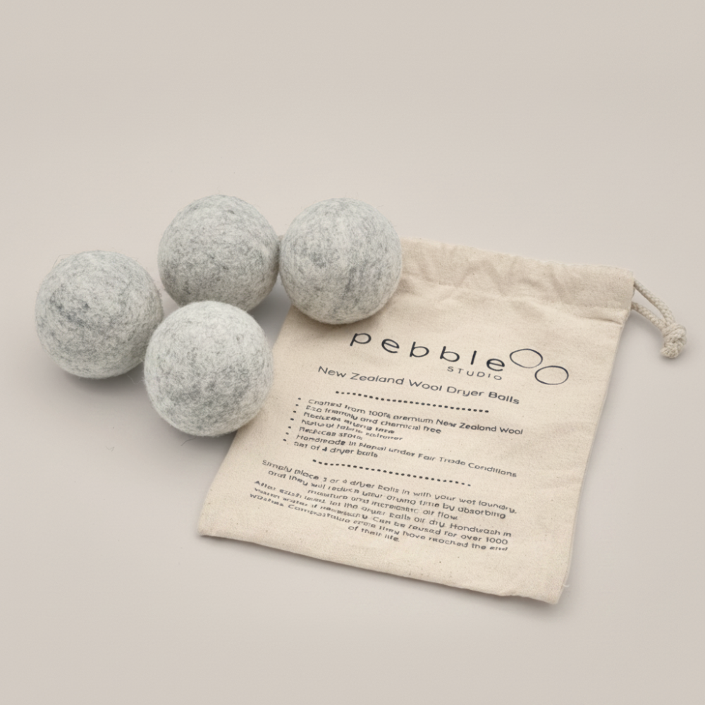 Four wool dryer balls with a branded drawstring bag on a beige background