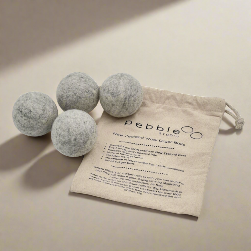 Four wool dryer balls with a branded drawstring bag on a neutral background