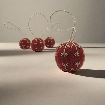Red felt ball ornaments with string on a light surface