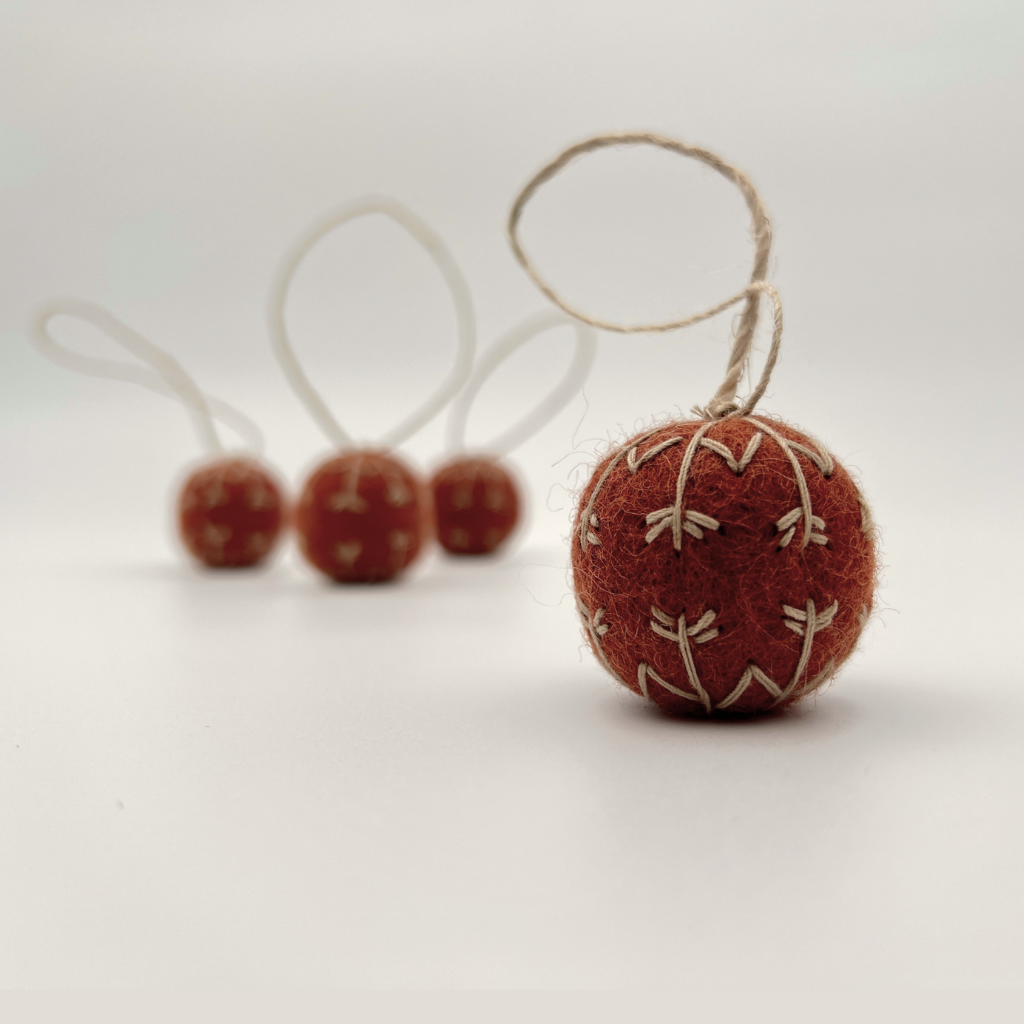 Red felt ball ornament with string on a white background
