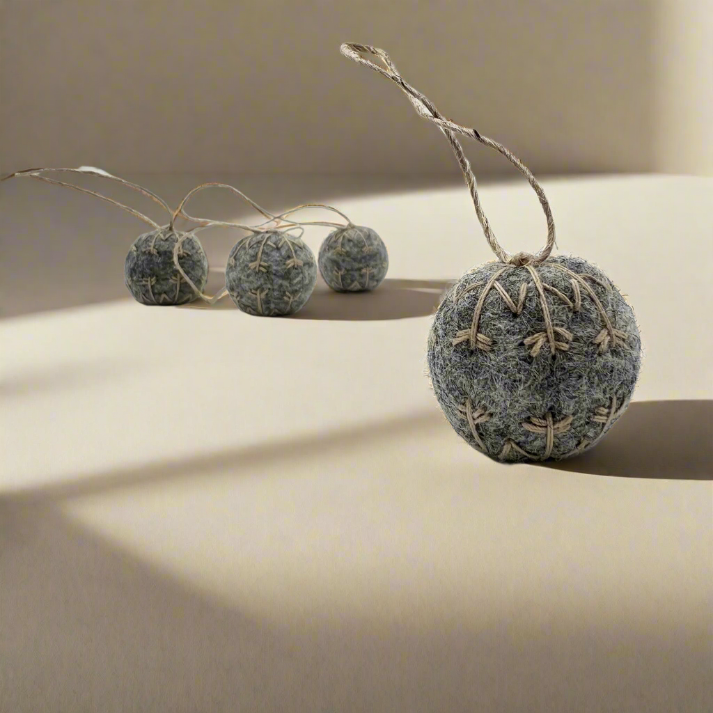 Four small felt snowflakes in Charcoal Marle with beige stitching.