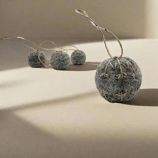 Four small felt snowflakes in Charcoal Marle with beige stitching.
