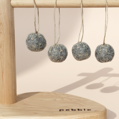 Four small felt snowflakes in Charcoal Marle with beige stitching, hanging from a wooden stand