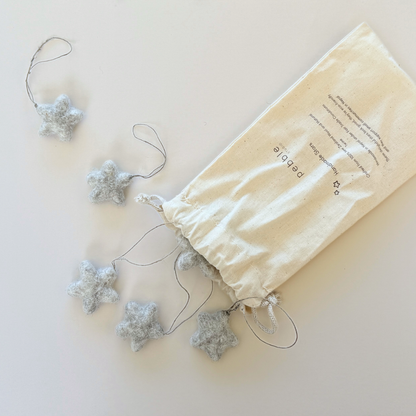 Star-shaped decorations on strings with a branded drawstring bag on a light background