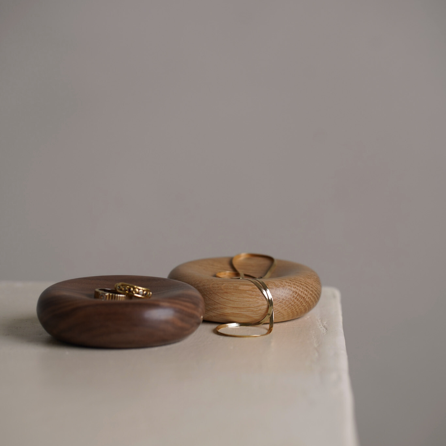 Two small wood decorative pillows in with jewellery. The bowls are made from oak and walnut