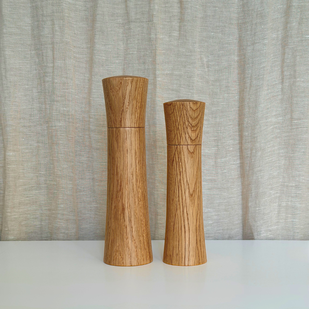 Set of Medium and Large Pebble Studio Salt & Pepper Mills in American Oak. Minimalist design on a neutral background