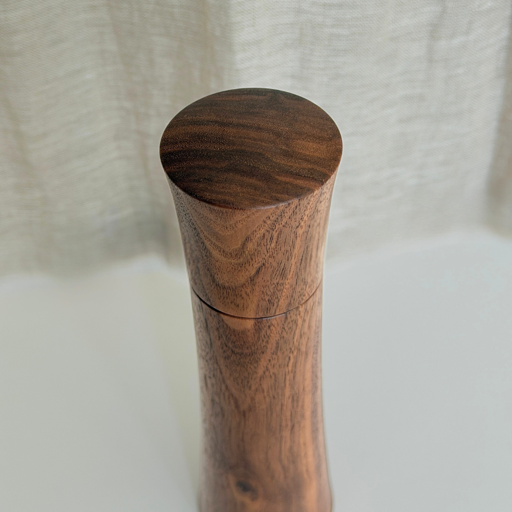 Minimalist curved top of a Pebble Studio handcrafted Walnut salt & pepper mill in Medium size