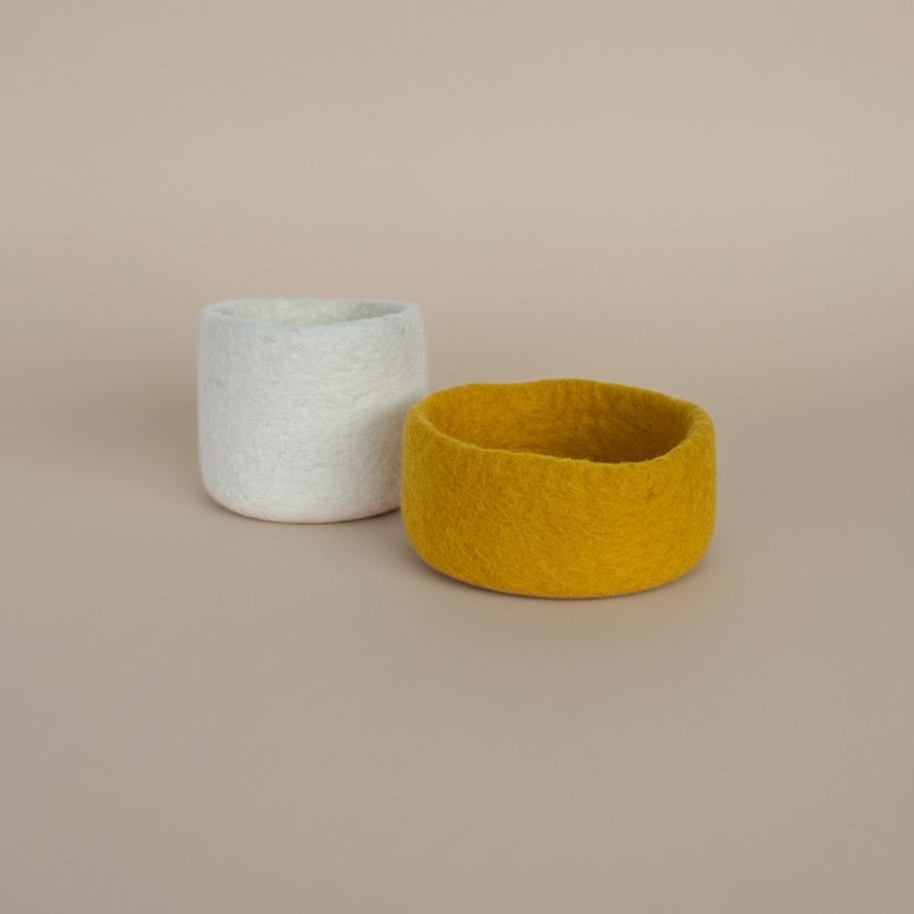 Loft Wool Felt Extra Small Basket  in Snow sitting behind a Sunflower Yellow Bowl- natural white wool felt catchall basket on a light background