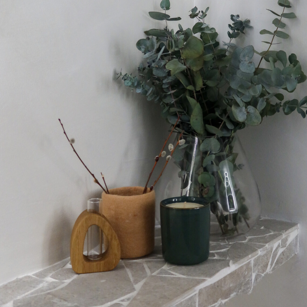Decorative vases with plants on a stone ledge against a plain wall